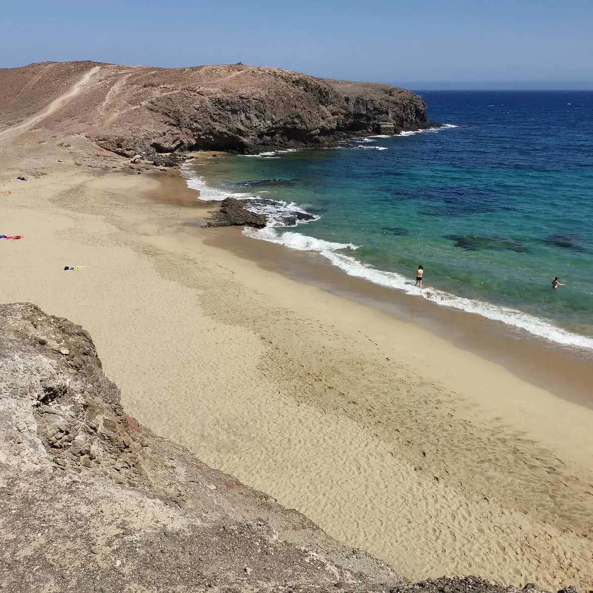 Small golden cove with clear turquoise water below a rocky headland at Papagayo