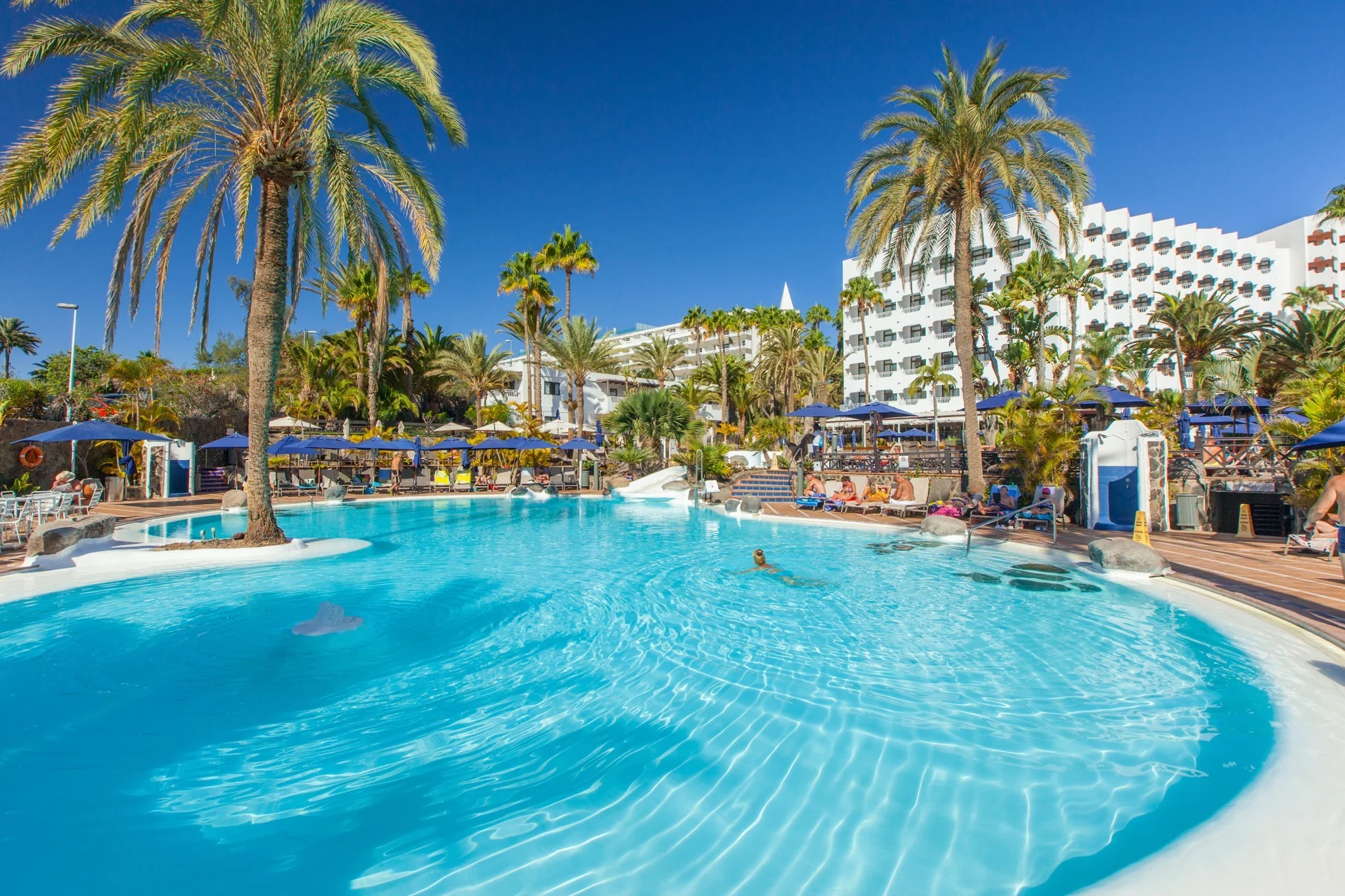 Large lagoon-style pool with palm trees at Corallium Beach by Lopesan Hotels in San Agustín, Gran Canaria