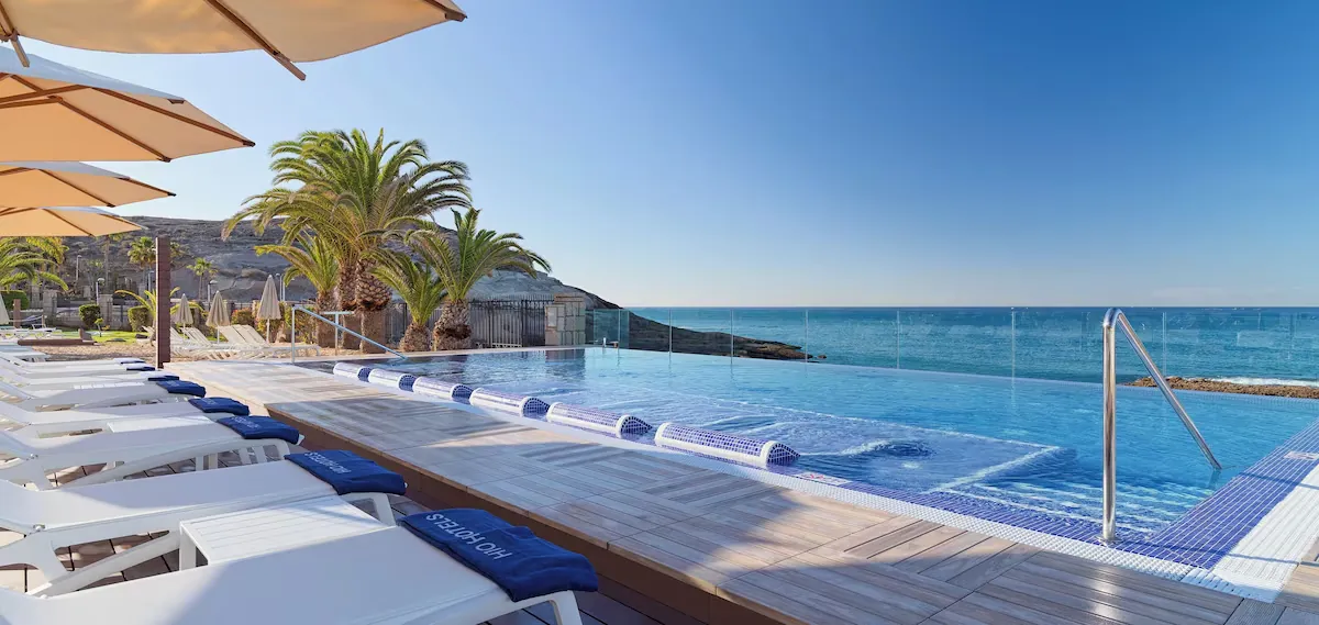 Infinity pool and sun loungers overlooking the sea at H10 Costa Adeje Palace, La Caleta
