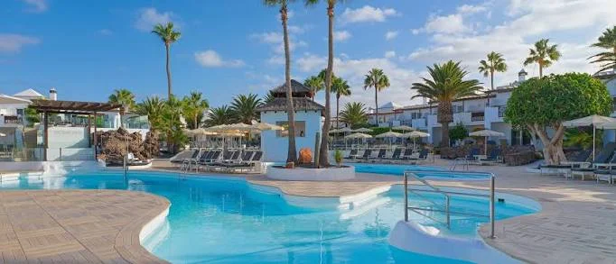 Pool area surrounded by palm trees at H10 White Suites near Playa Blanca, Lanzarote