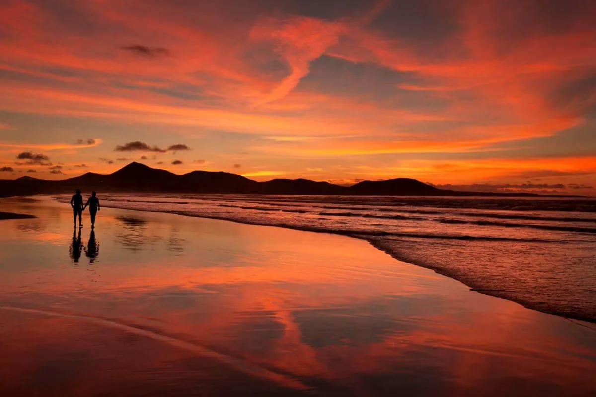 Couple walking along Playa de Famara at sunset, Lanzarote