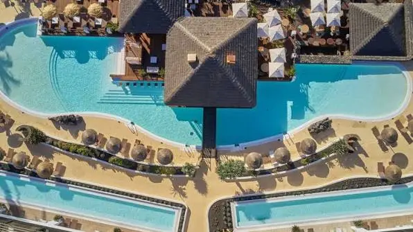Aerial view of the pool complex and thatched sun loungers at Secrets Lanzarote Resort & Spa in Puerto Calero