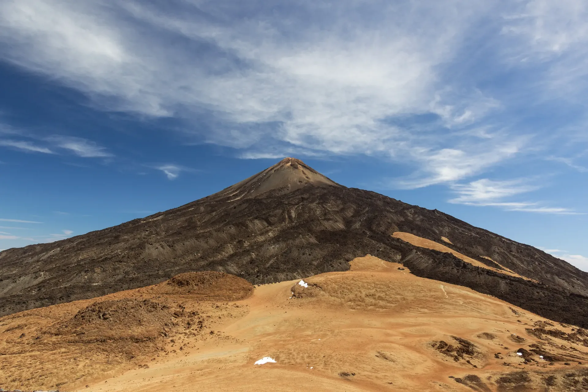The summit cone of Mount Teide above ochre pumice slopes and lava