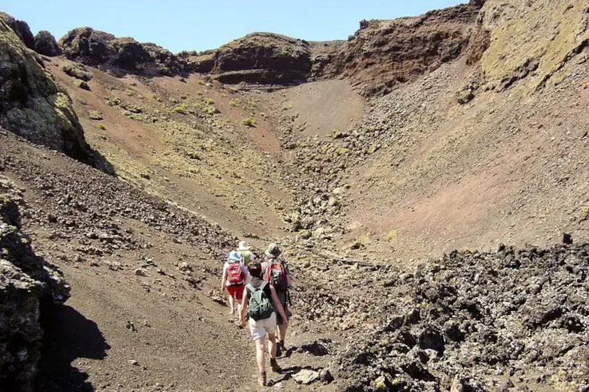 Hikers walking into a volcanic crater in Lanzarote